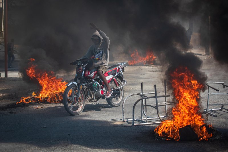A person rides a motorcycle through street fires in Port-au-Prince, Haiti, on March 1, 2024, a day after gang violence left at least five dead and 20 injured. File Photo by Johnson Sabin/EPA-EFE